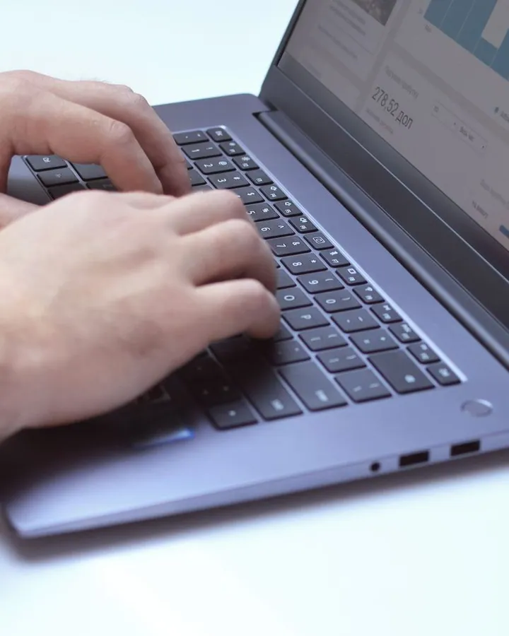 Hands using a laptop displaying analytics charts
