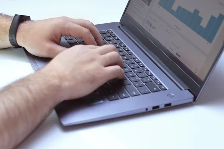 Hands using a laptop displaying analytics charts