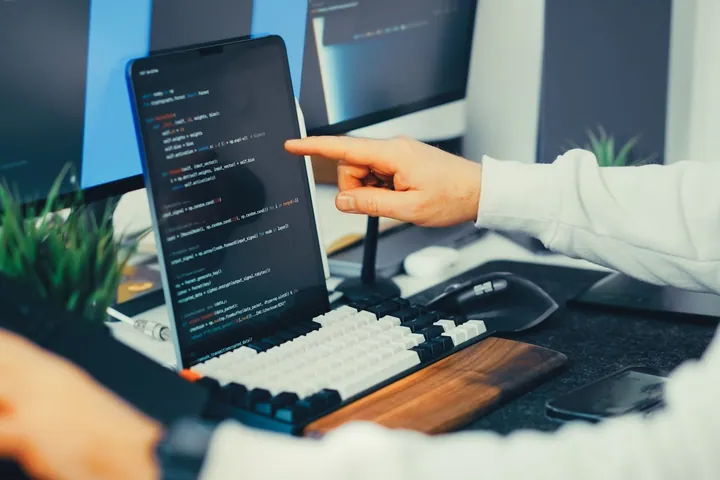 Person working on code at a laptop and monitor